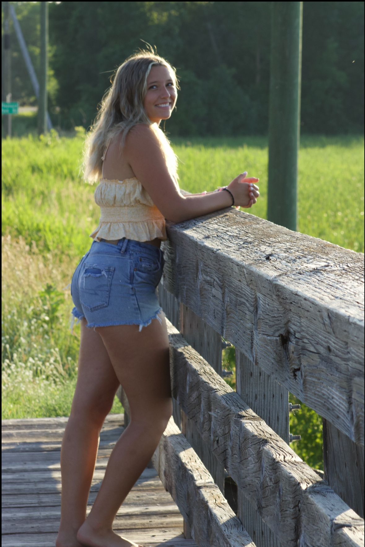 Casual outdoor portrait session on rustic wooden fence during sunset.