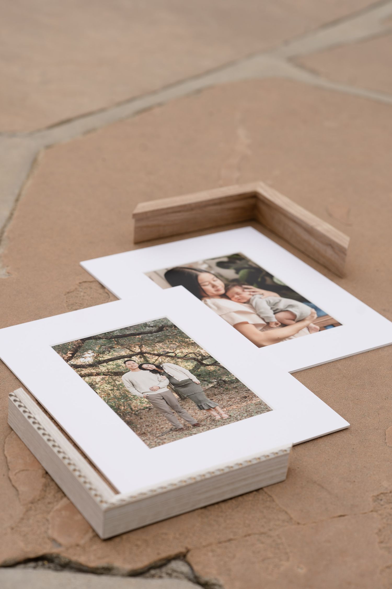 Two framed family portrait photos displayed on stone surface, one in wooden frame and one in white matted frame.