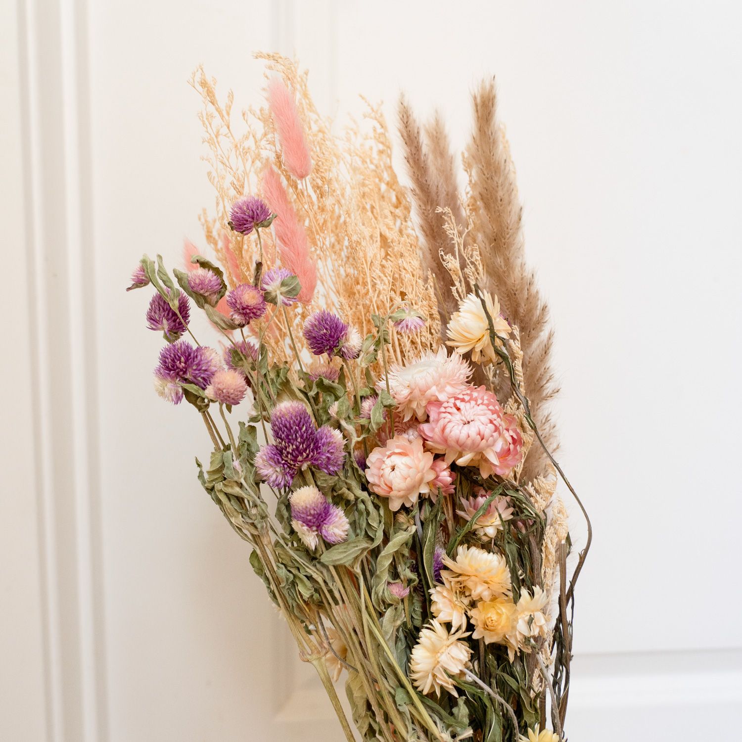 Colorful dried flower bouquet with purple globe amaranth, pink pampas grass, and yellow blooms.