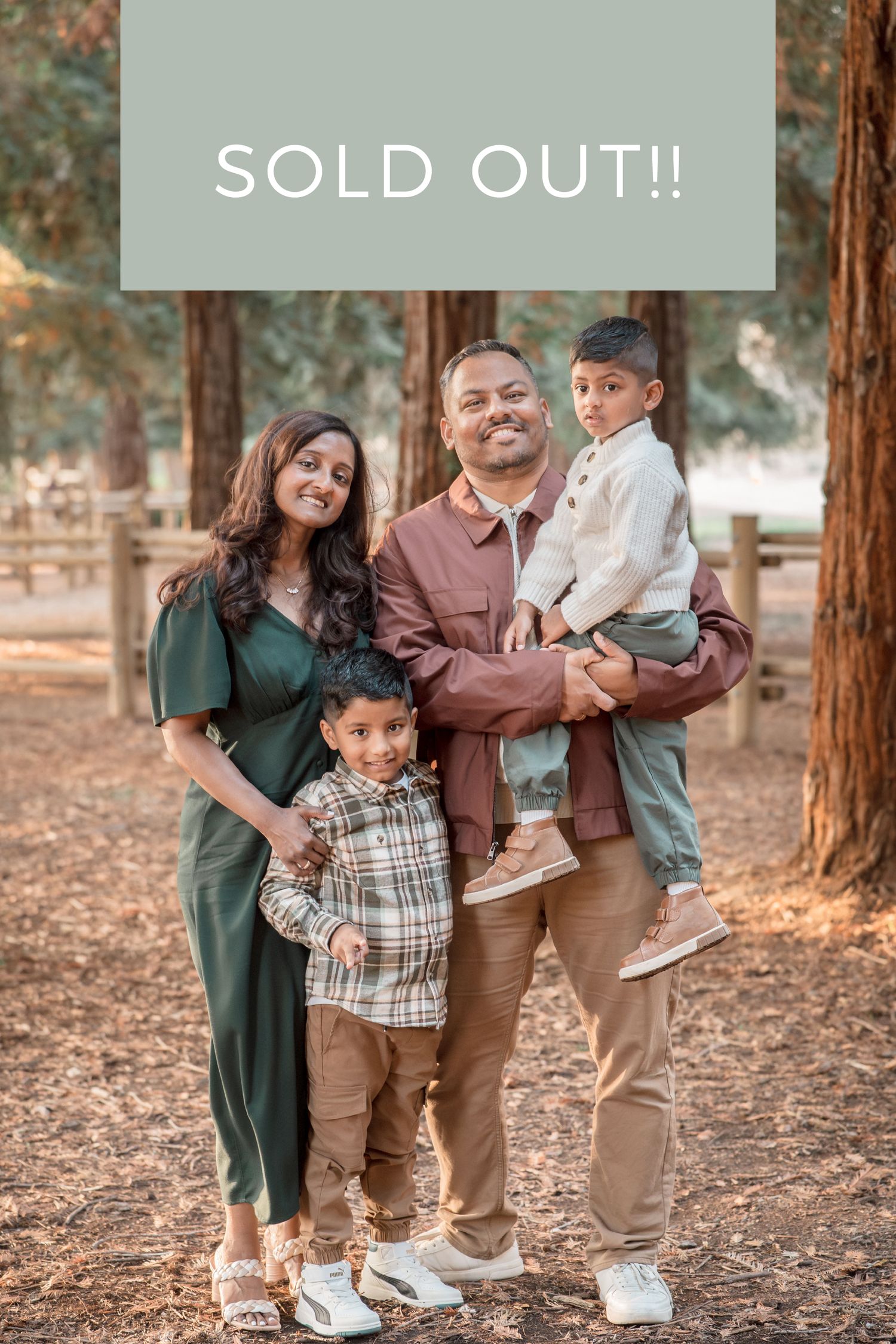 A family of four poses together in a redwood forest with a sold out banner overlay.