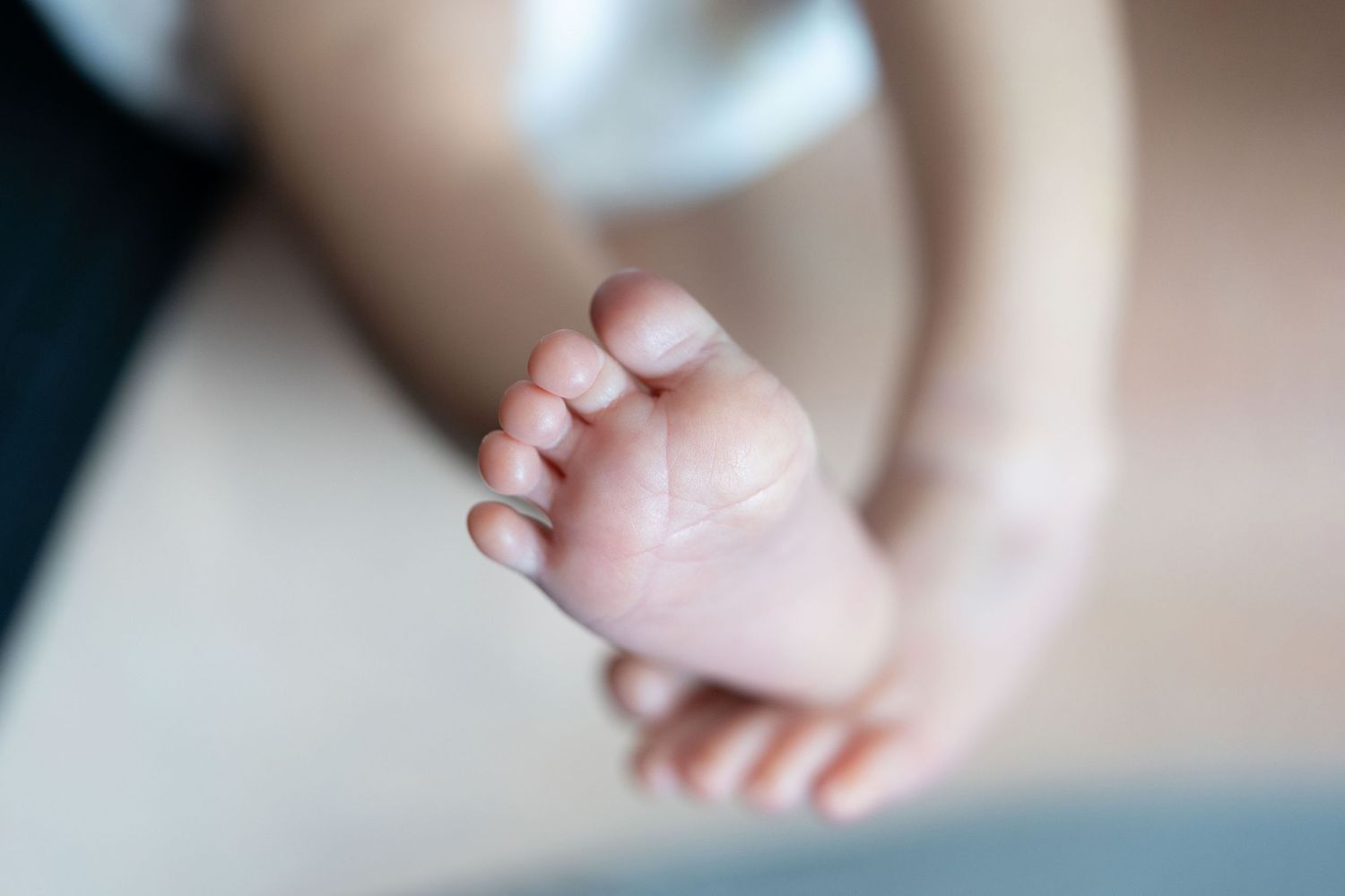 Close-up of a newborn baby's tiny foot being gently held.