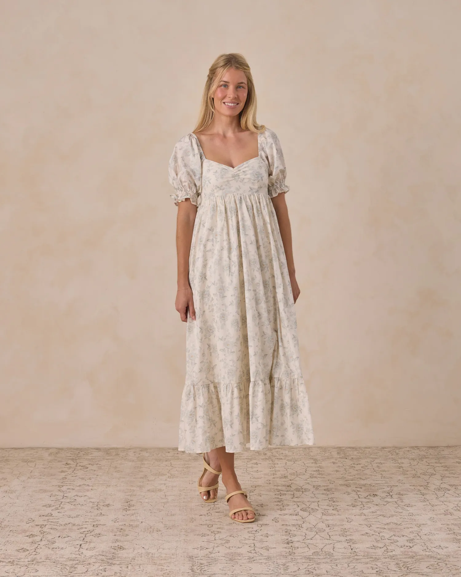 Blonde woman in a floral print puff sleeve midi dress with sweetheart neckline and ruffle hem.