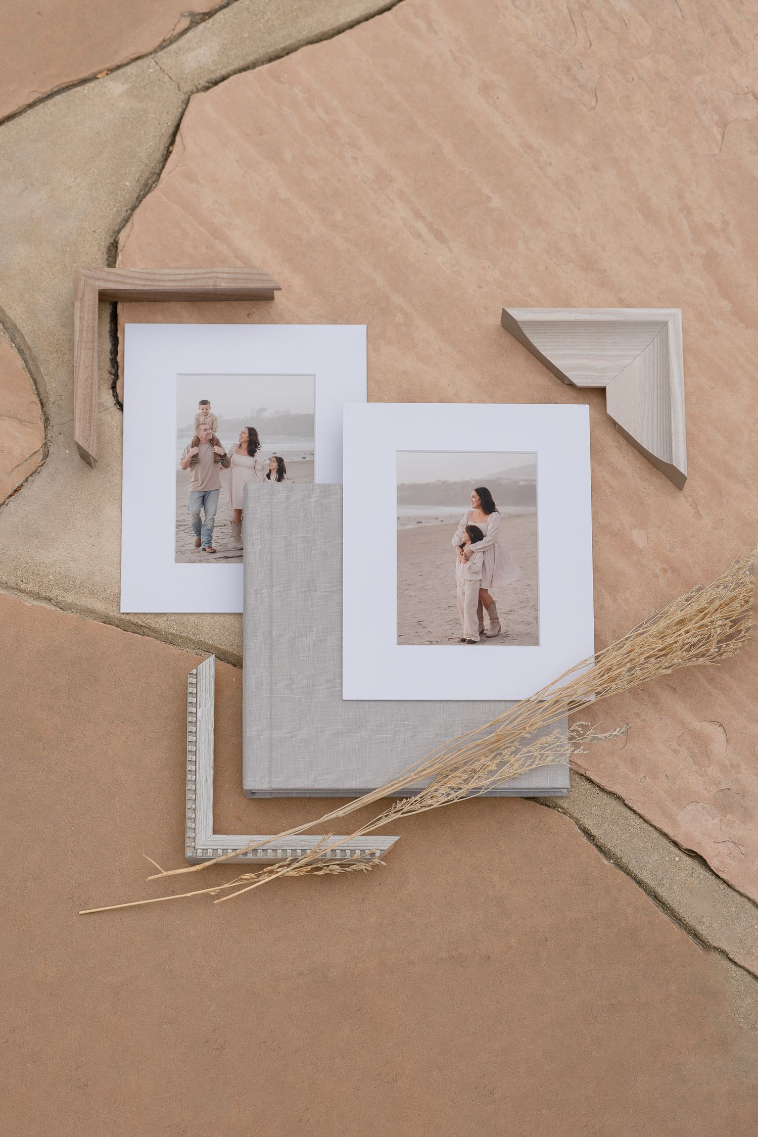 Two framed family photos displayed on neutral stone surface with dried grass and decorative frame corners.