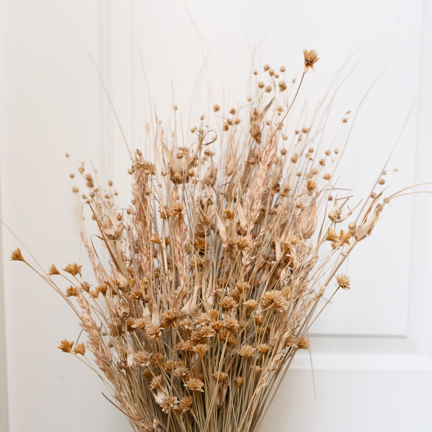 Rustic dried wildflower bouquet with golden straw flowers and grasses in natural beige tones.