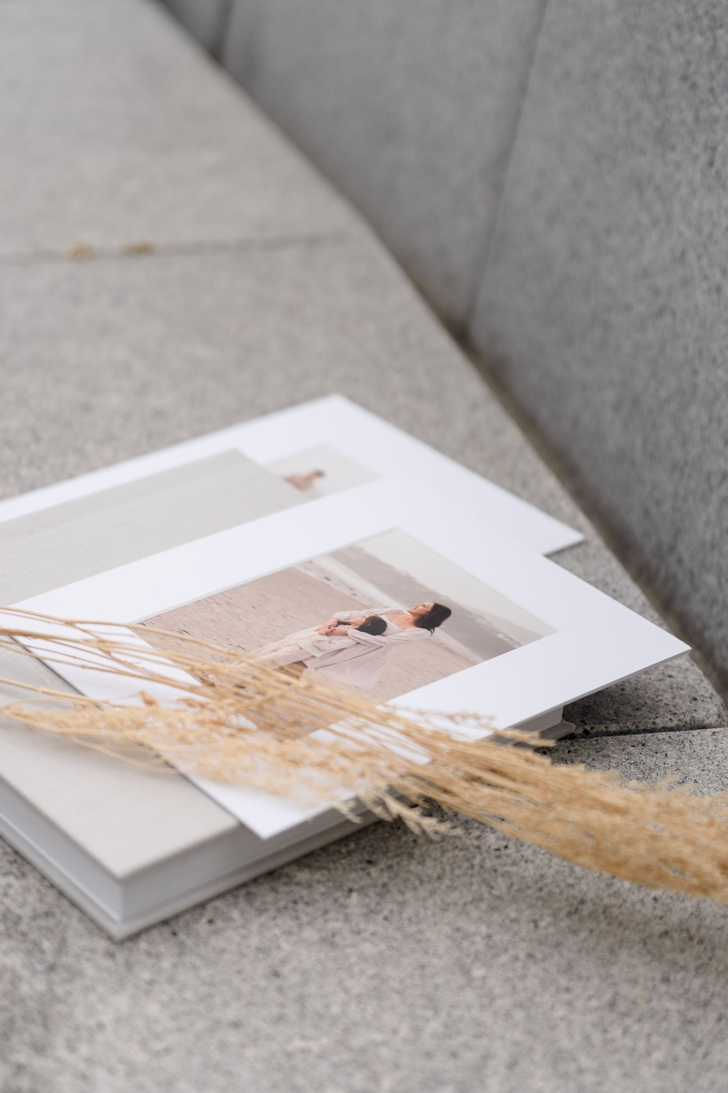 Minimalist wedding photos and dried pampas grass arranged on a gray concrete surface.