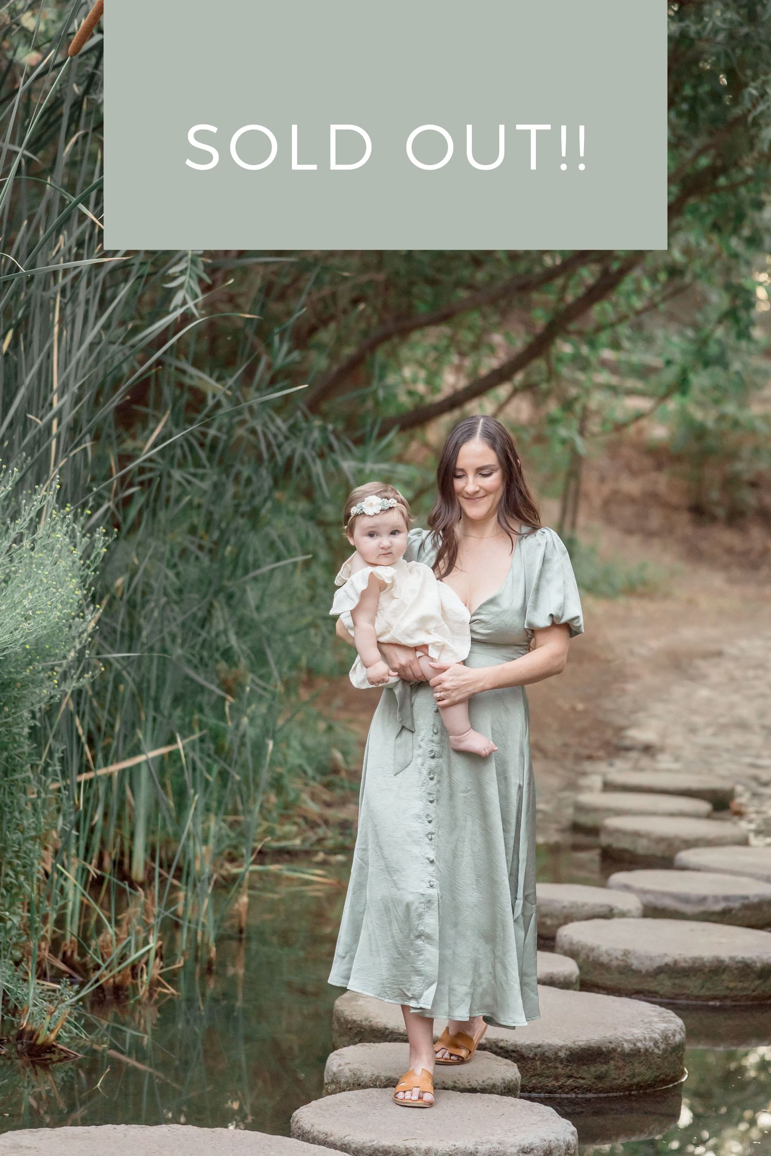 Woman in mint button-down dress carrying infant on garden stepping stones, sold out.