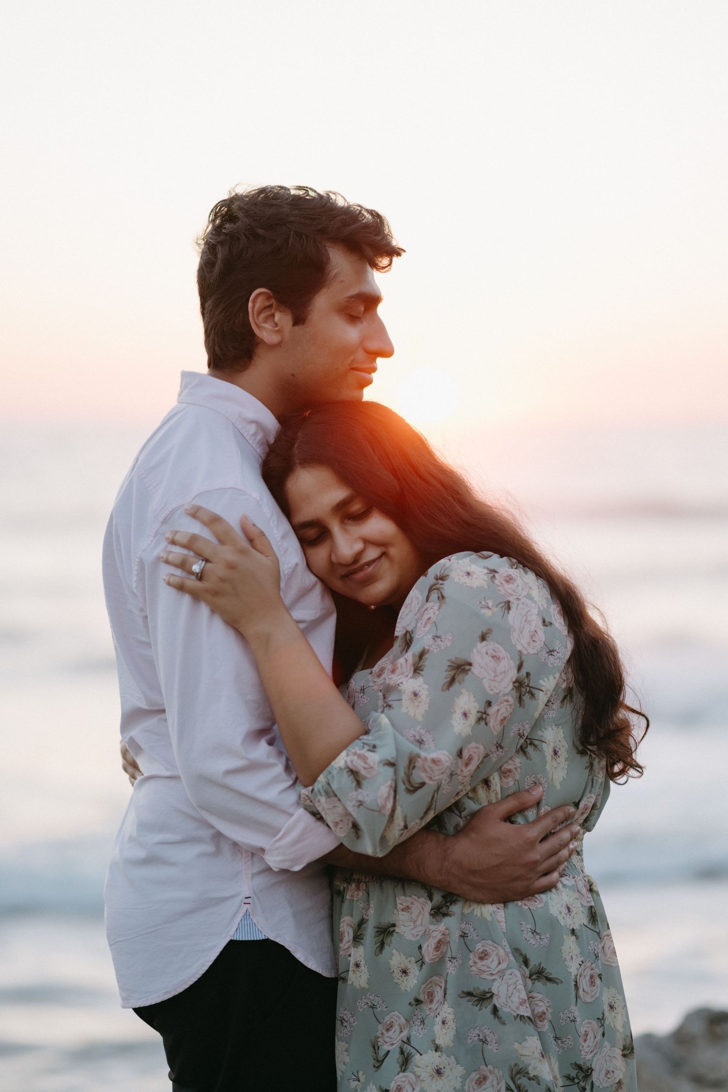 Tender moment between couple during sunset beach photo session.
