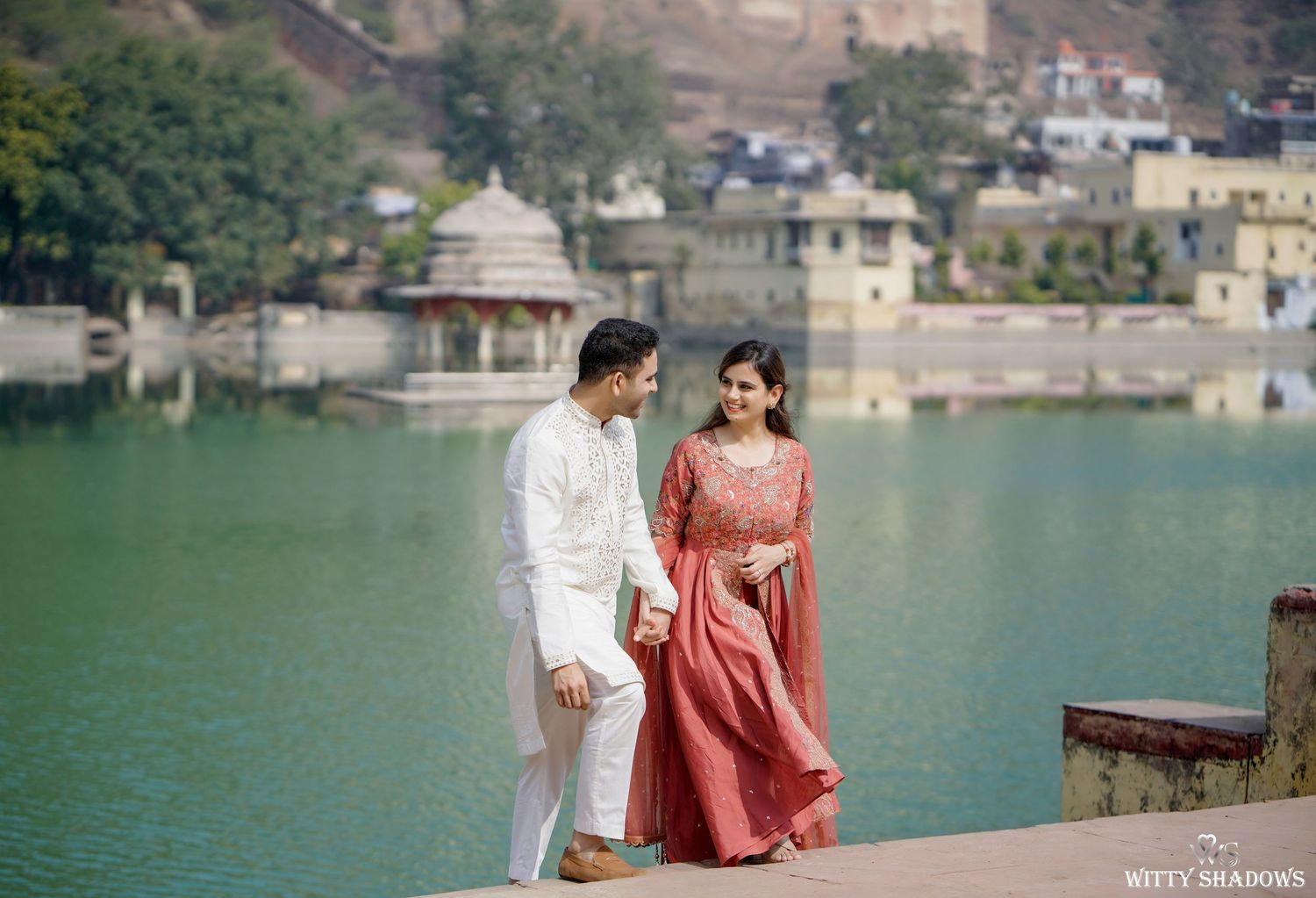 Serene lakeside setting with architecture and mountains reflecting in turquoise waters.