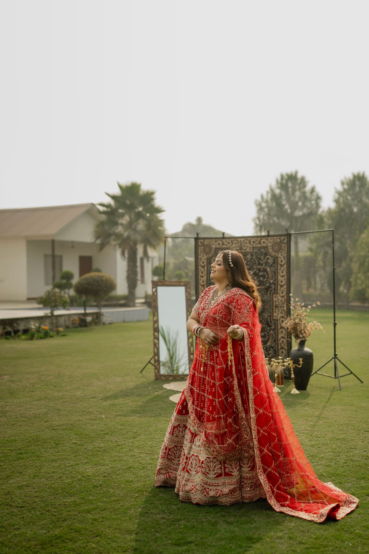 A sequence of outdoor bridal portraits showing a red and gold traditional Indian lehenga against a green lawn backdrop.
