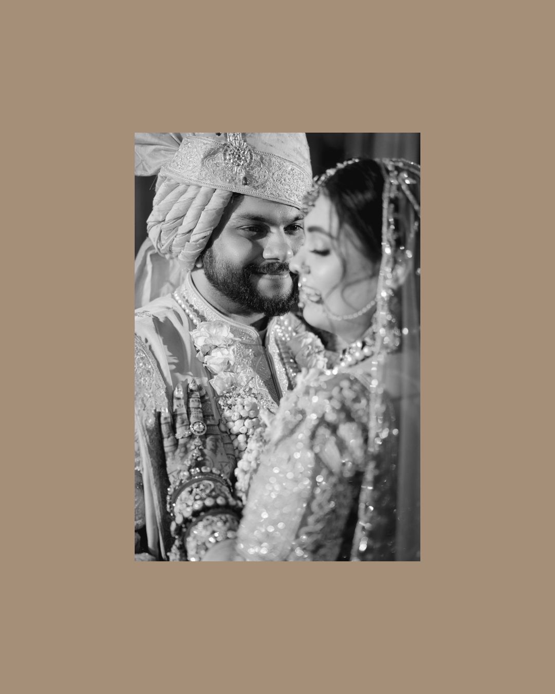Black and white photo of an Indian bride and groom in traditional wedding attire sharing an intimate moment.