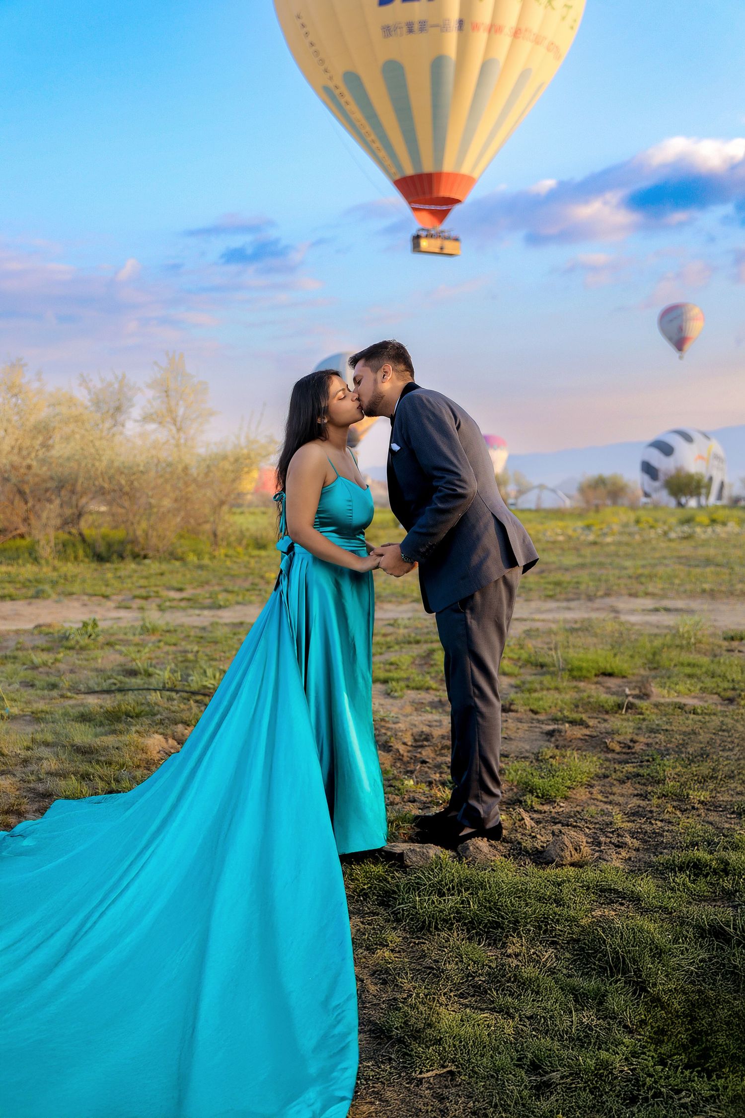 Romantic photoshoot with hot air balloons floating in blue sky background.