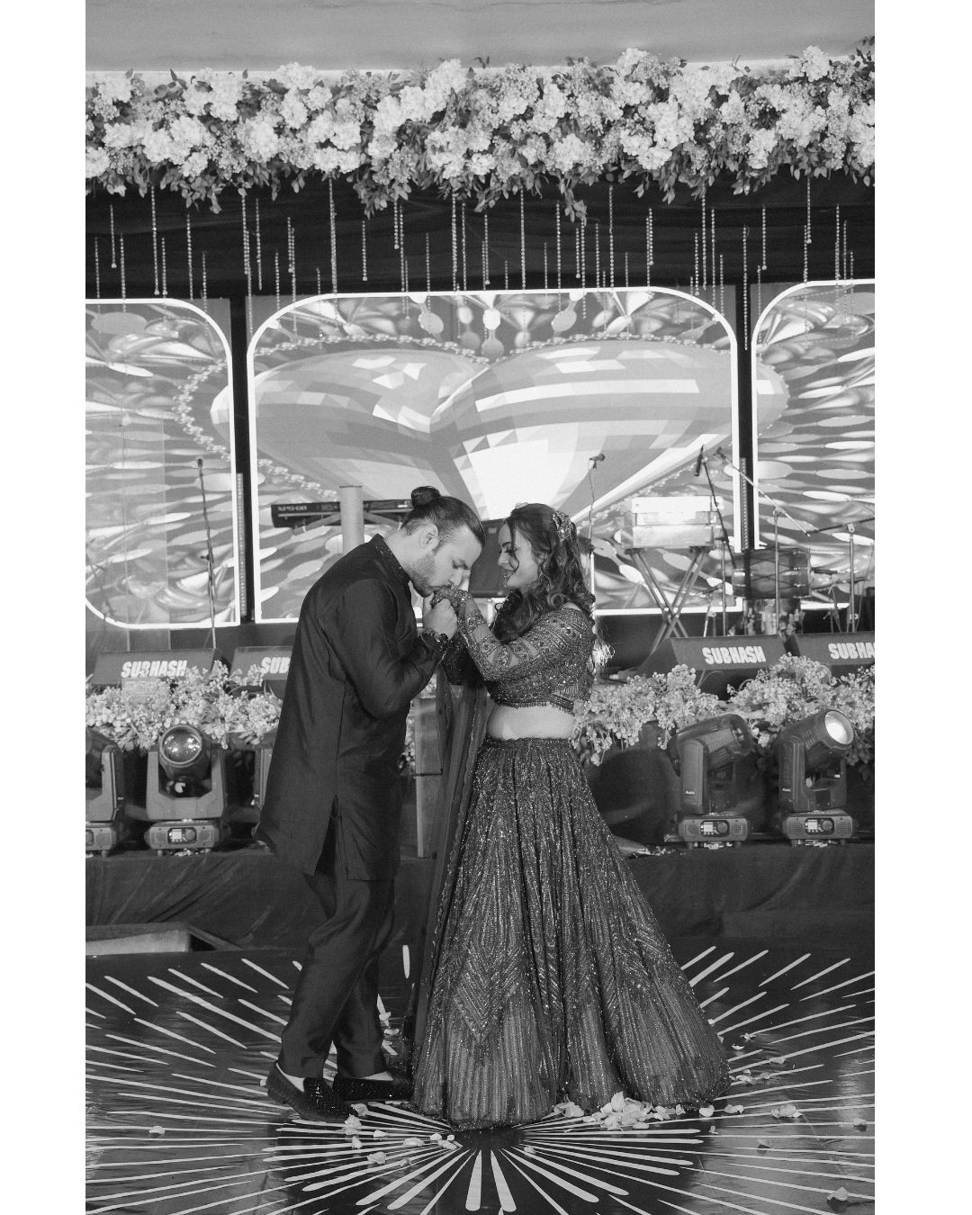 Black and white photo of a couple sharing a romantic dance at an elegant Indian wedding celebration.