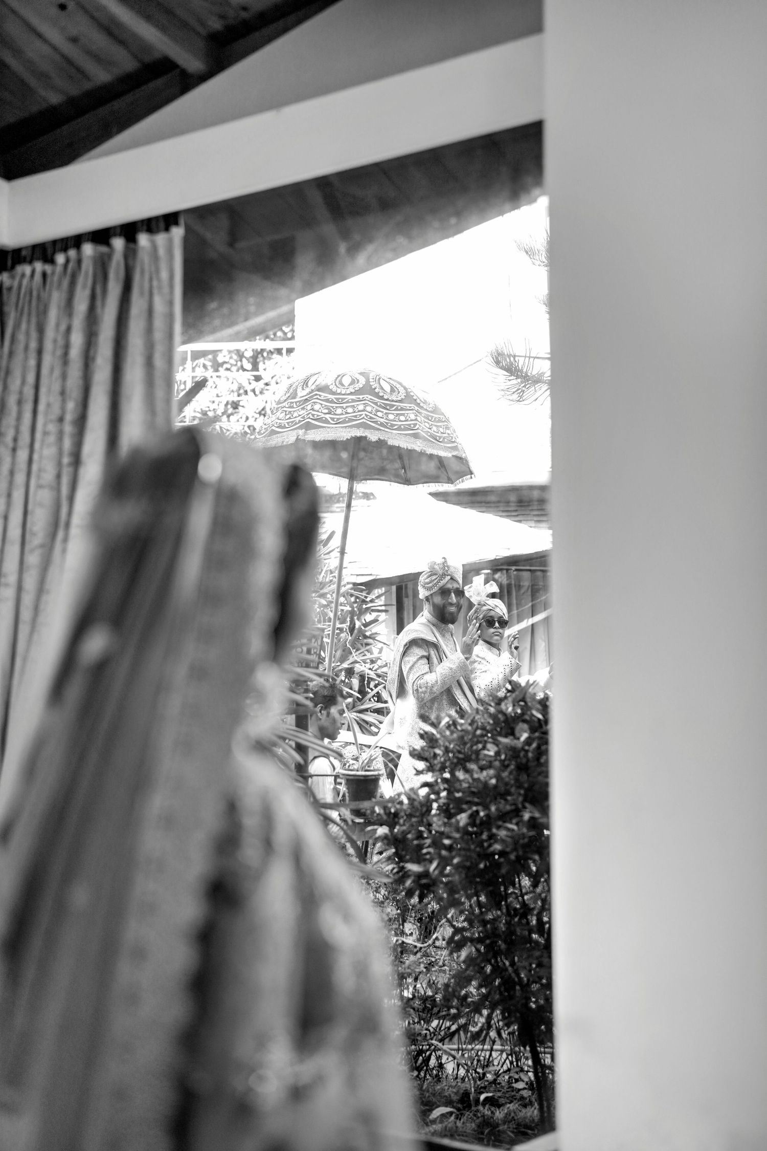 Black and white window view with curtains framing an outdoor garden scene.