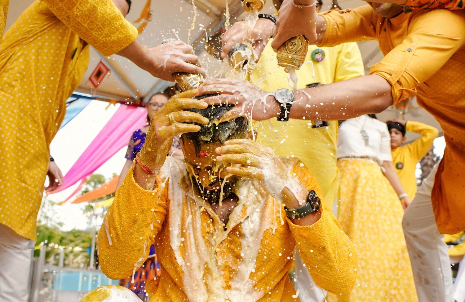 Close-up details of hands performing traditional Indian wedding rituals with yellow decorations.