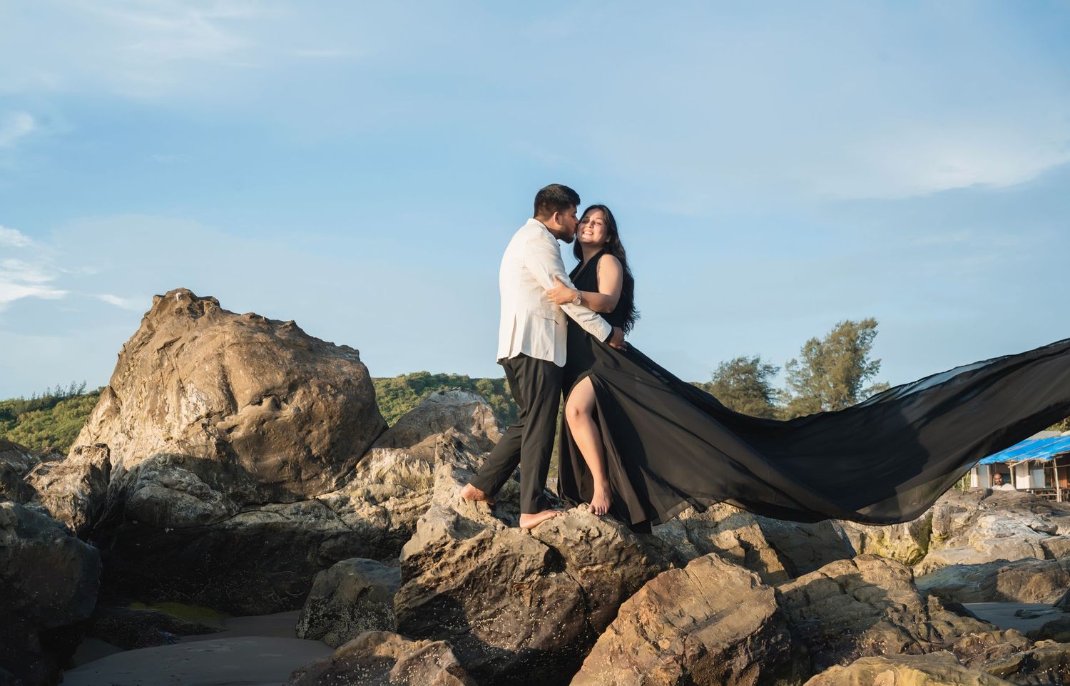 Black fabric flows dramatically against coastal rocks and ocean backdrop.
