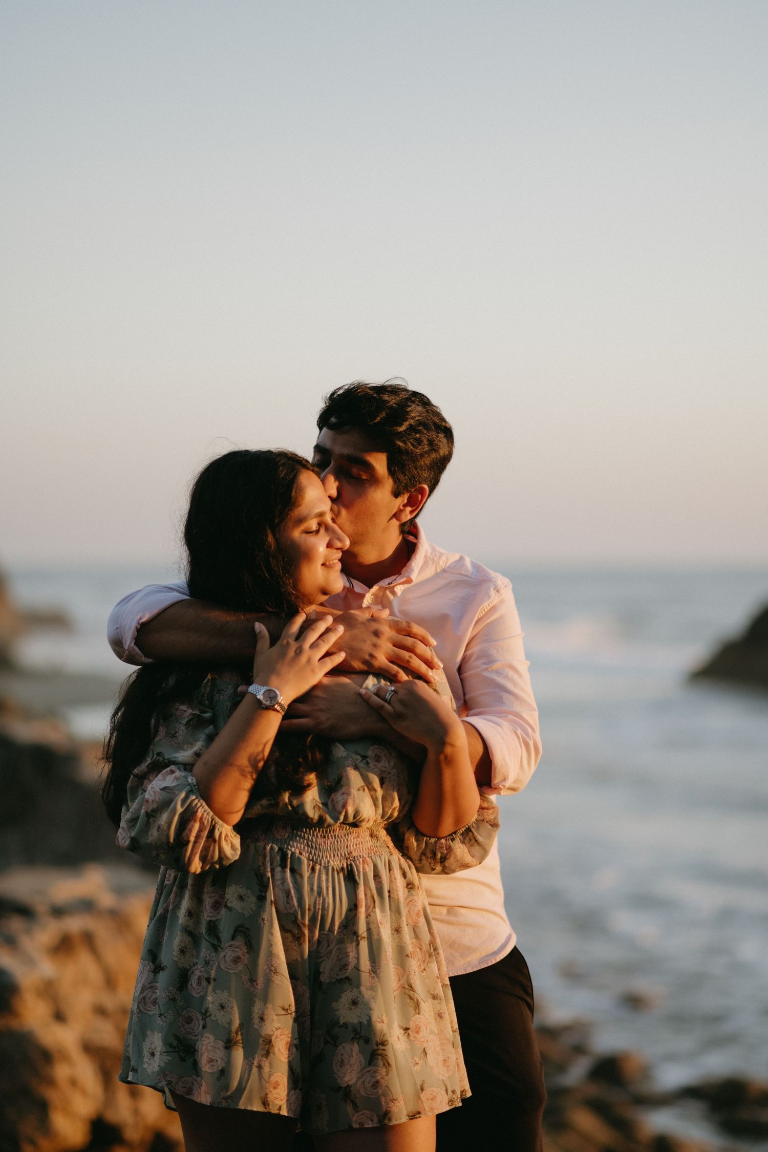 Romantic couple shares intimate moment at sunset by the ocean.