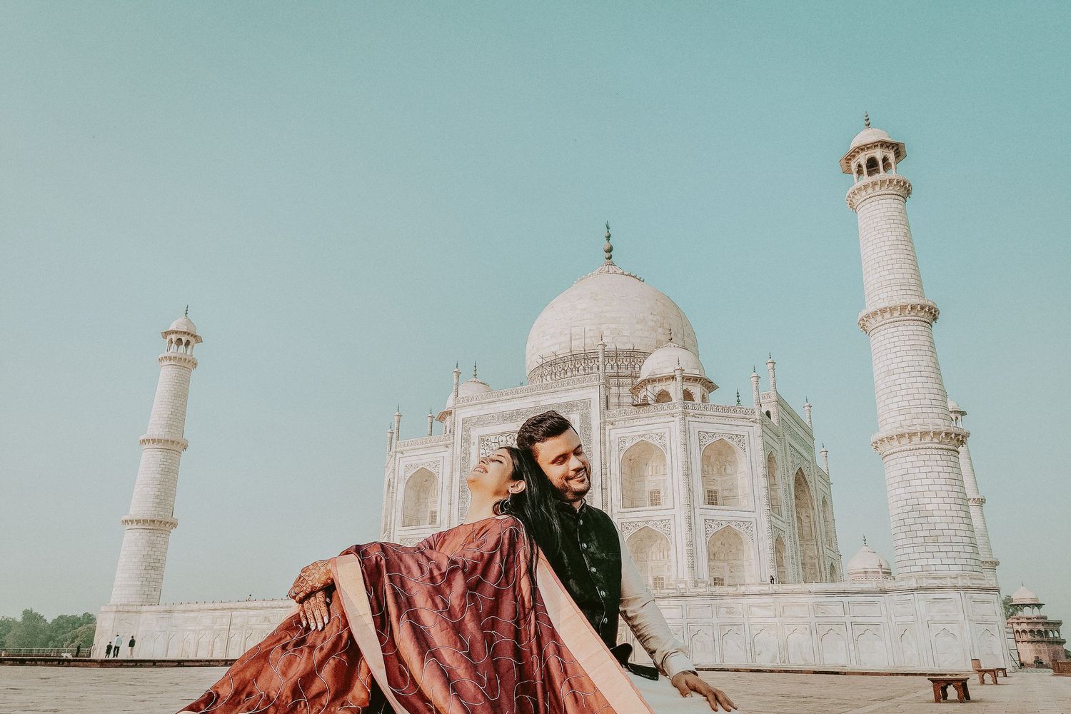 Couple posing romantically in front of the Taj Mahal in Agra, India, wearing traditional Indian attire.