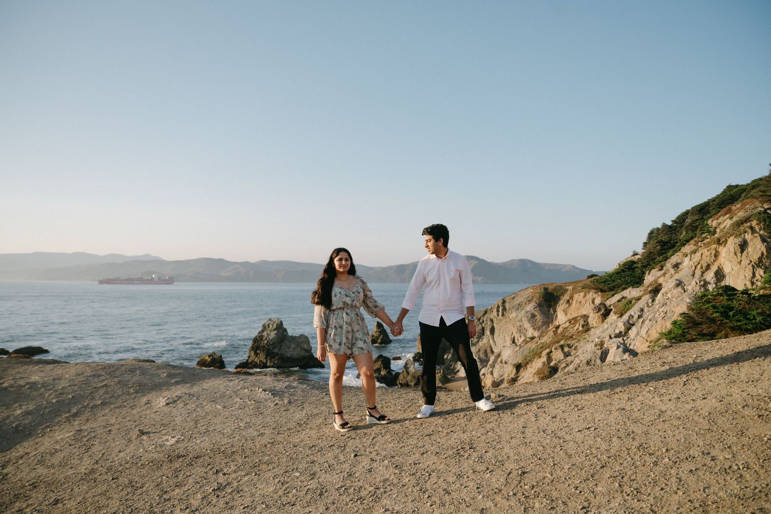 Wedding couple poses on scenic coastal cliffs overlooking the ocean.
