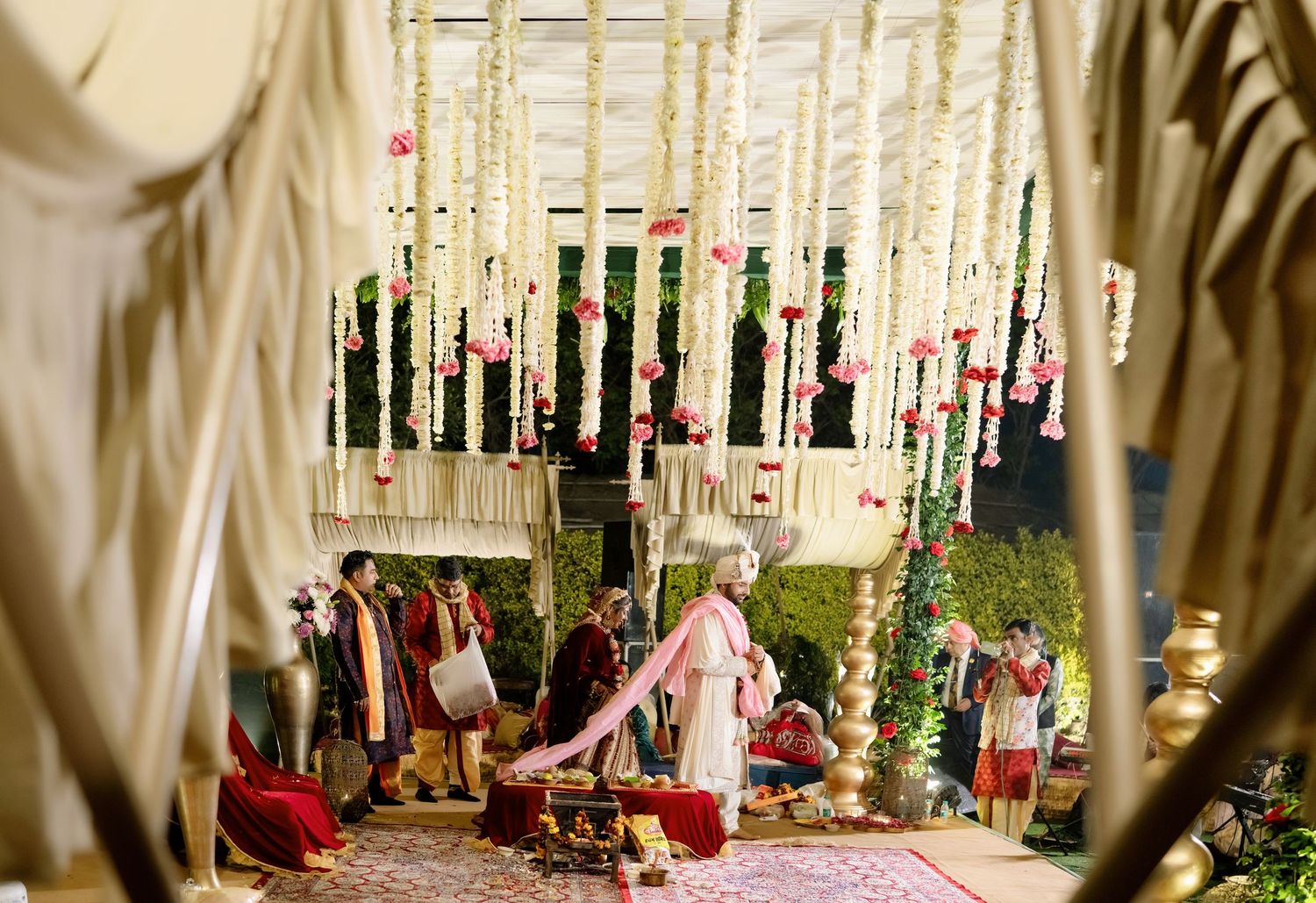 Elegant wedding venue decorated with hanging floral arrangements and white drapes creating a romantic atmosphere.