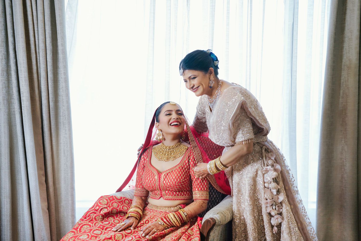Joyful moments shared during wedding preparations in flowing coral attire.