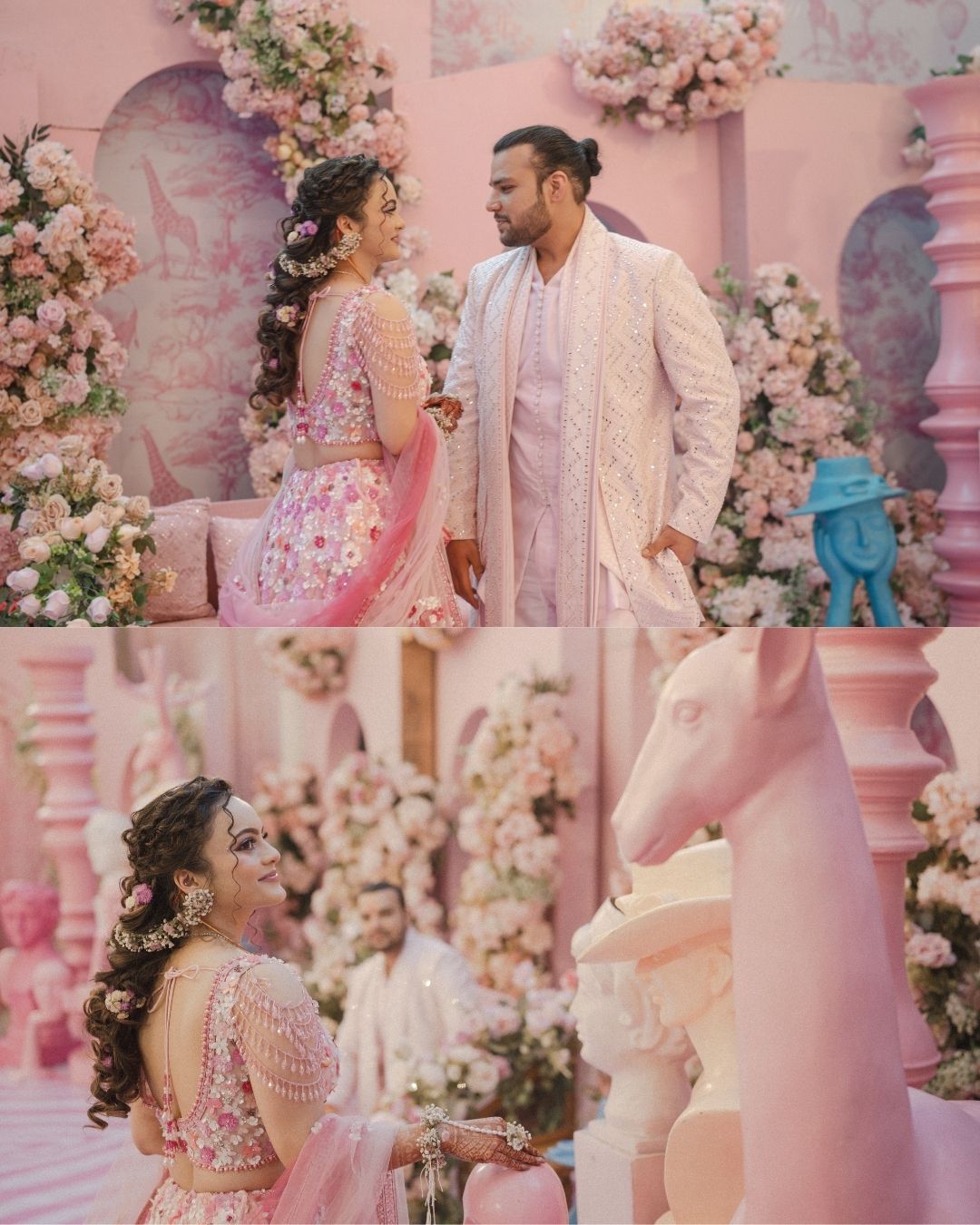 Couple in pink and white traditional Indian wedding attire posing among pink floral decorations and ornate pink architecture.