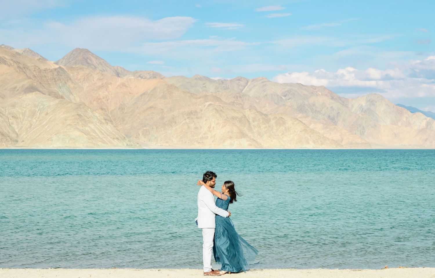 Turquoise waters of Pangong Lake contrast with arid mountains under clear blue skies.