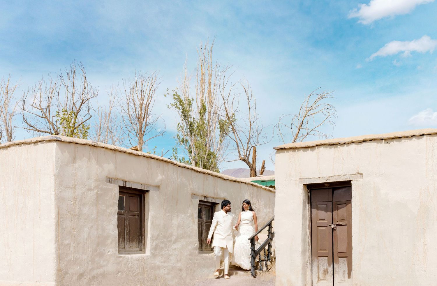 Traditional white adobe buildings with wooden doors set against a clear blue sky.