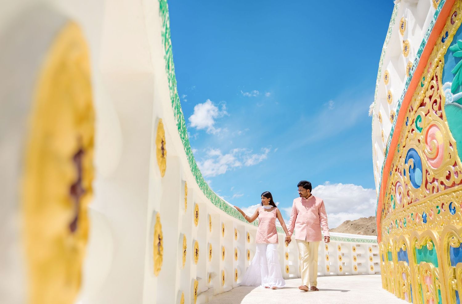 Bright yellow and turquoise painted temple corridor with ornate wall murals and decorative architecture.