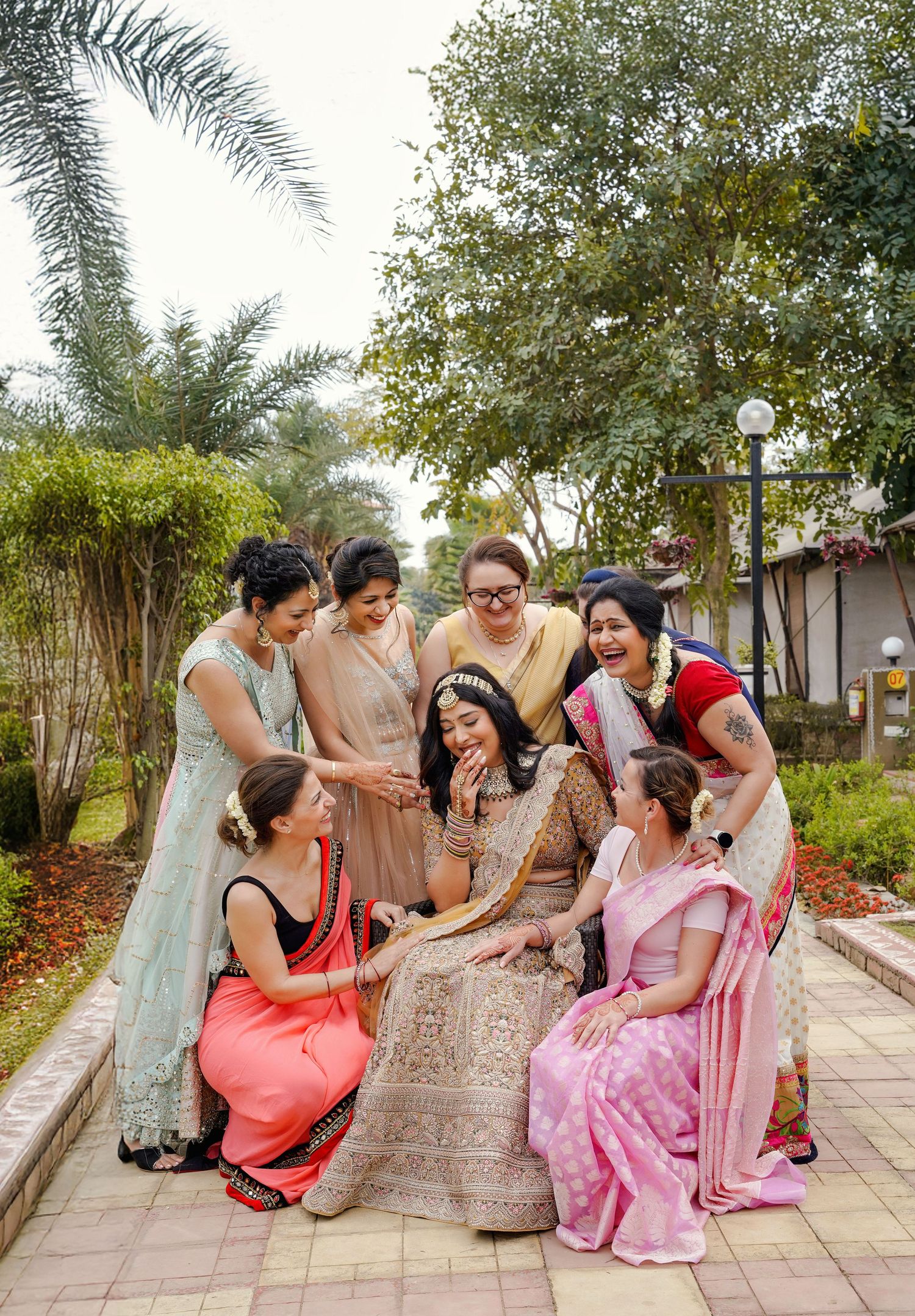 Group of women in traditional Indian attire sitting and laughing together on outdoor steps.
