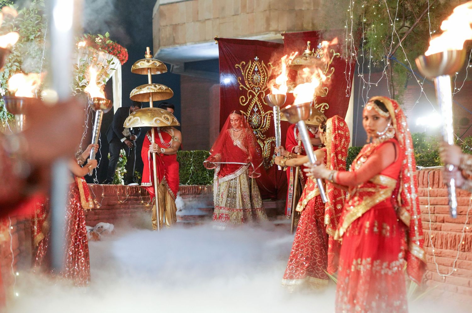 Traditional Indian wedding decor with ornate red and gold decorations and lighting.