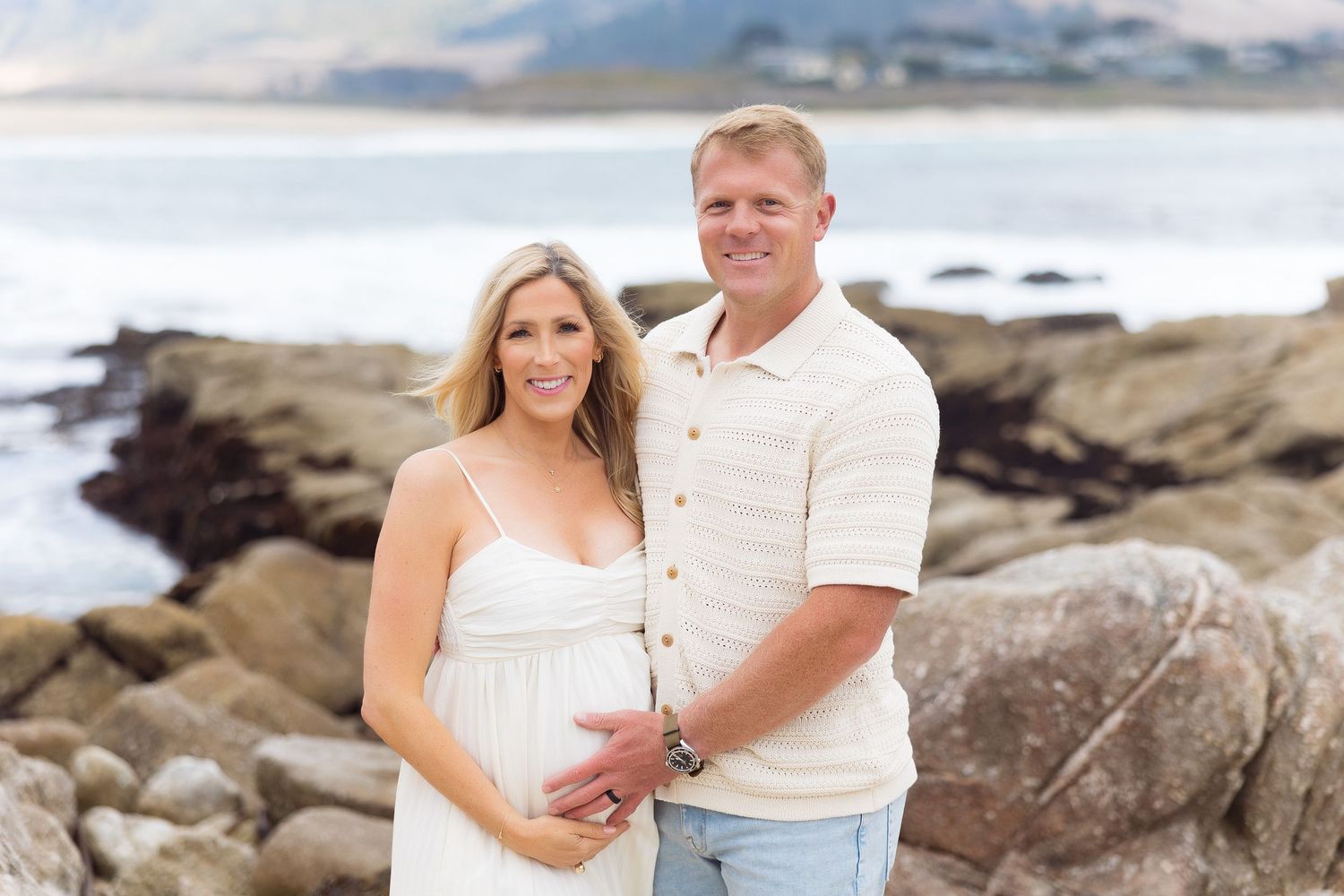 Romantic beach photoshoot among coastal rocks and waves at sunset.
