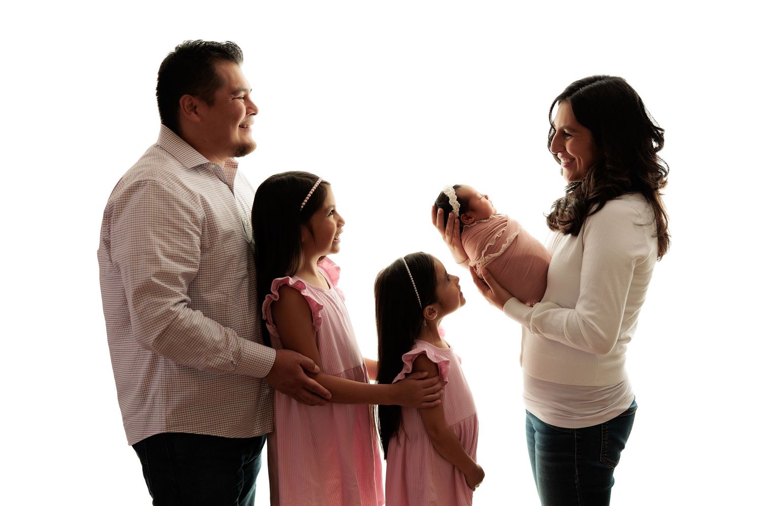 Family of four silhouetted against white background showing tender moment with newborn.