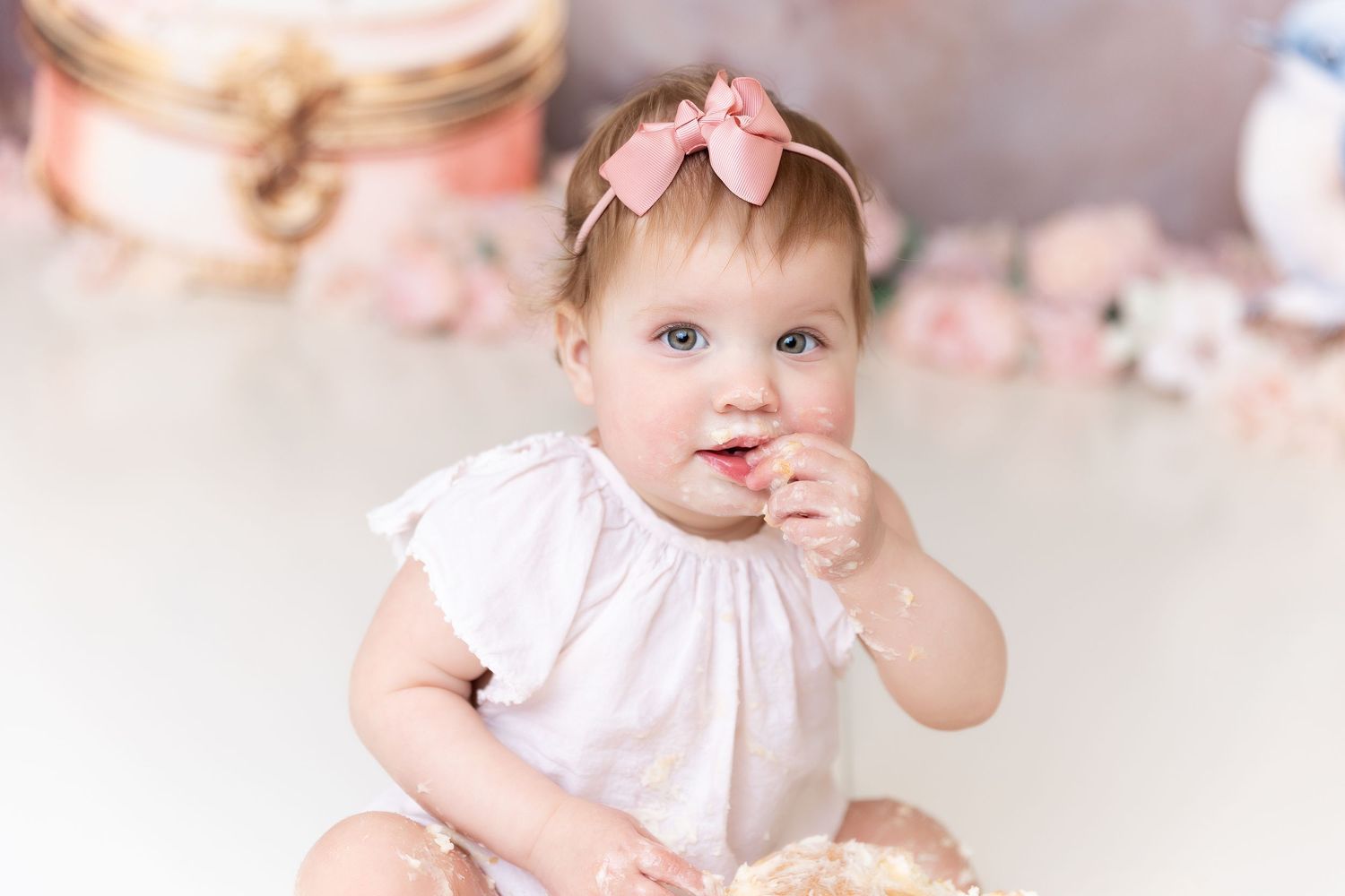 Soft pink tones highlight a delicate milestone photoshoot setup with floral decorations.