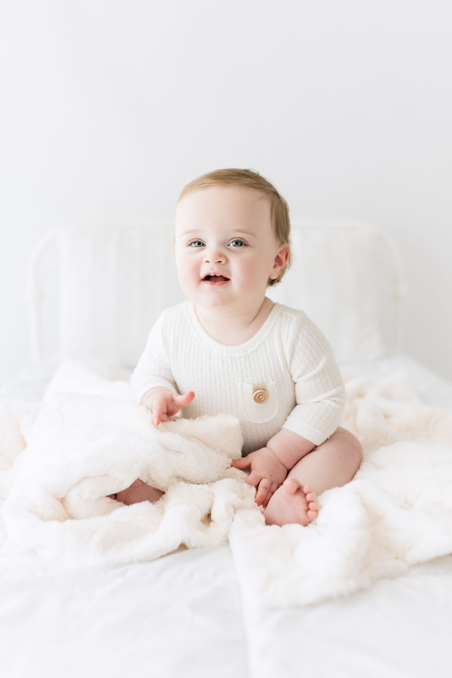 Bright white studio portrait featuring cozy knit outfit and soft textiles.