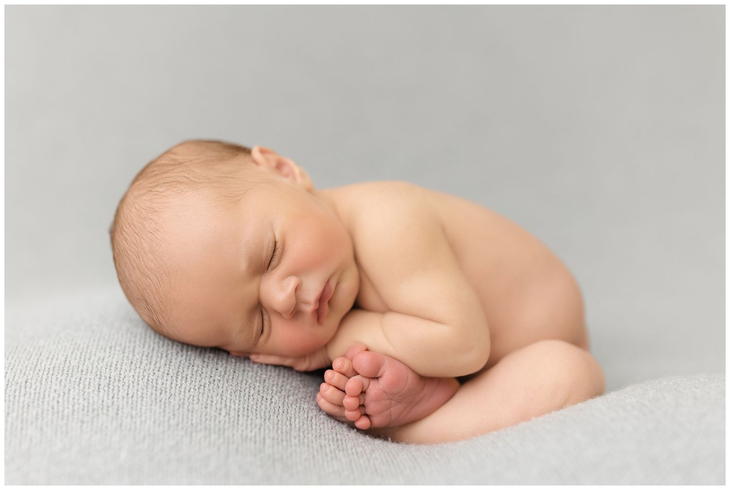 A series of peaceful sleeping newborn baby photos in black and white against soft white backgrounds.