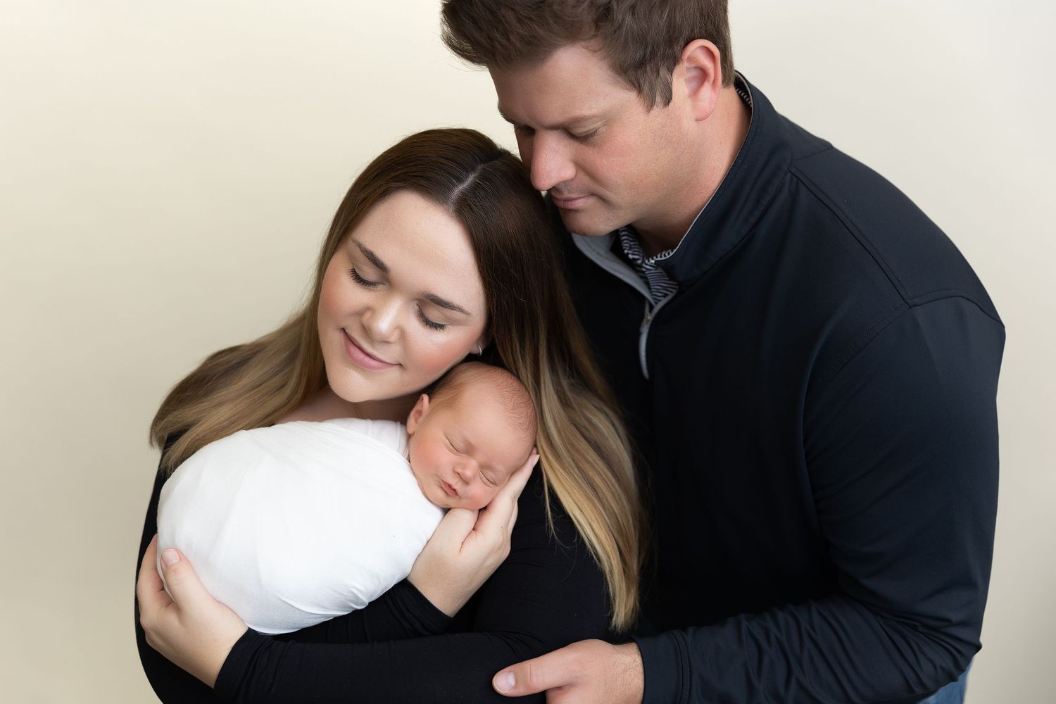 Intimate couple embracing in soft natural light against white background.