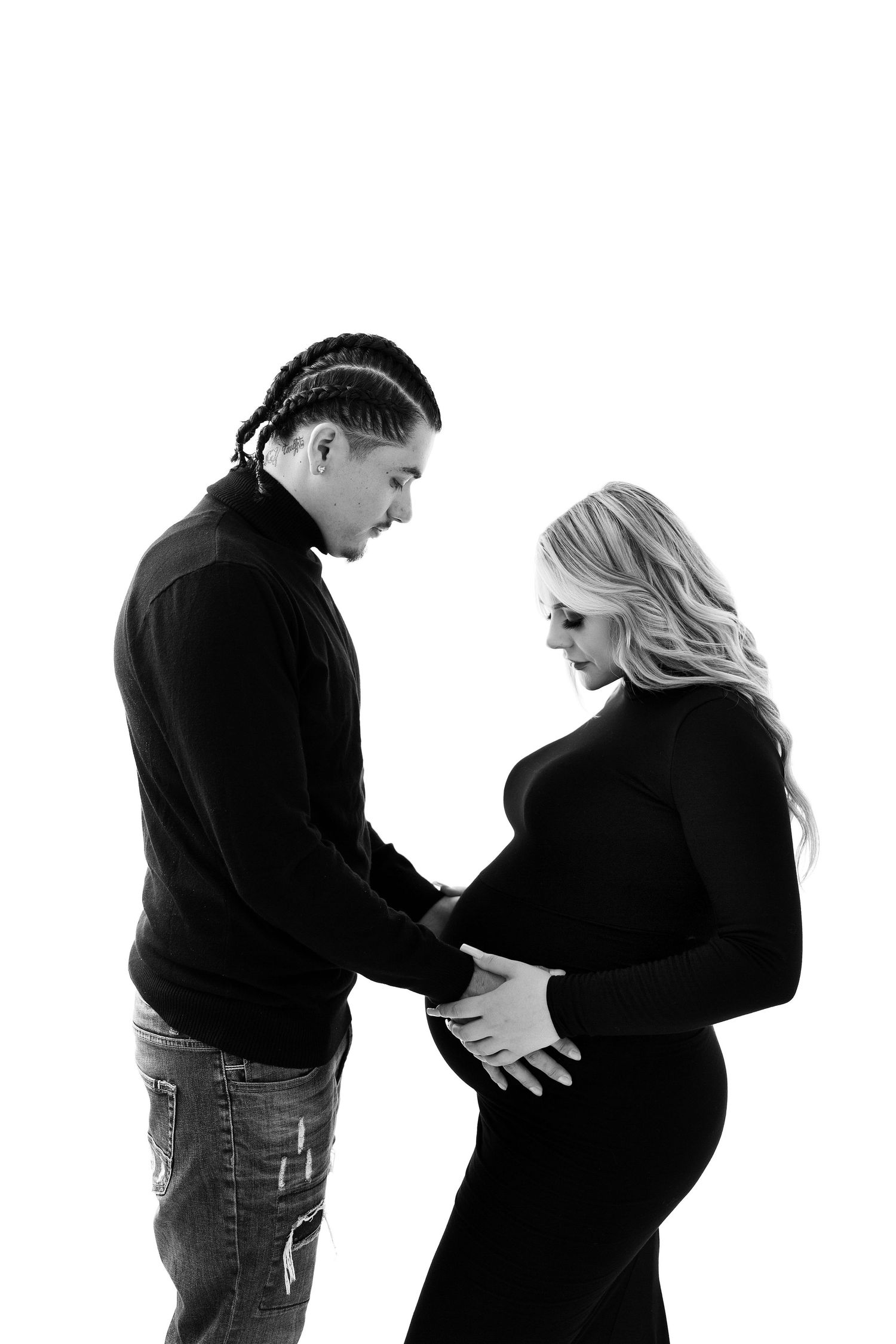 Black and white maternity session showing couple's tender moments against white background.