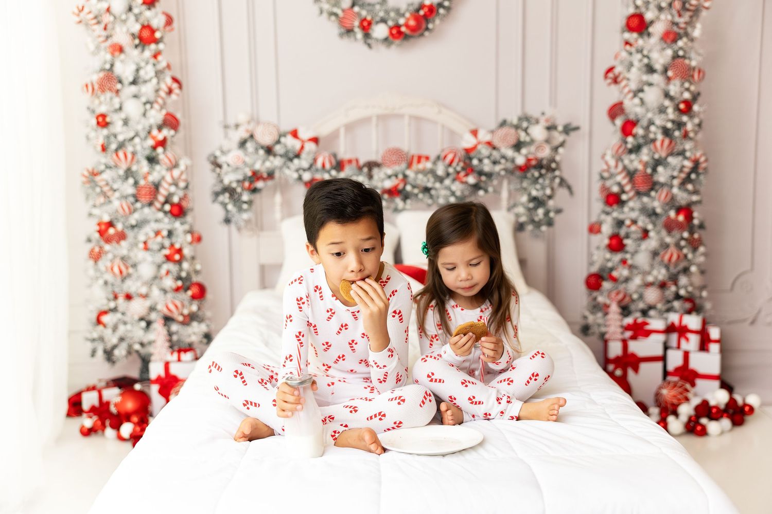 Playful holiday photo session with kids in pajamas surrounded by Christmas decor.