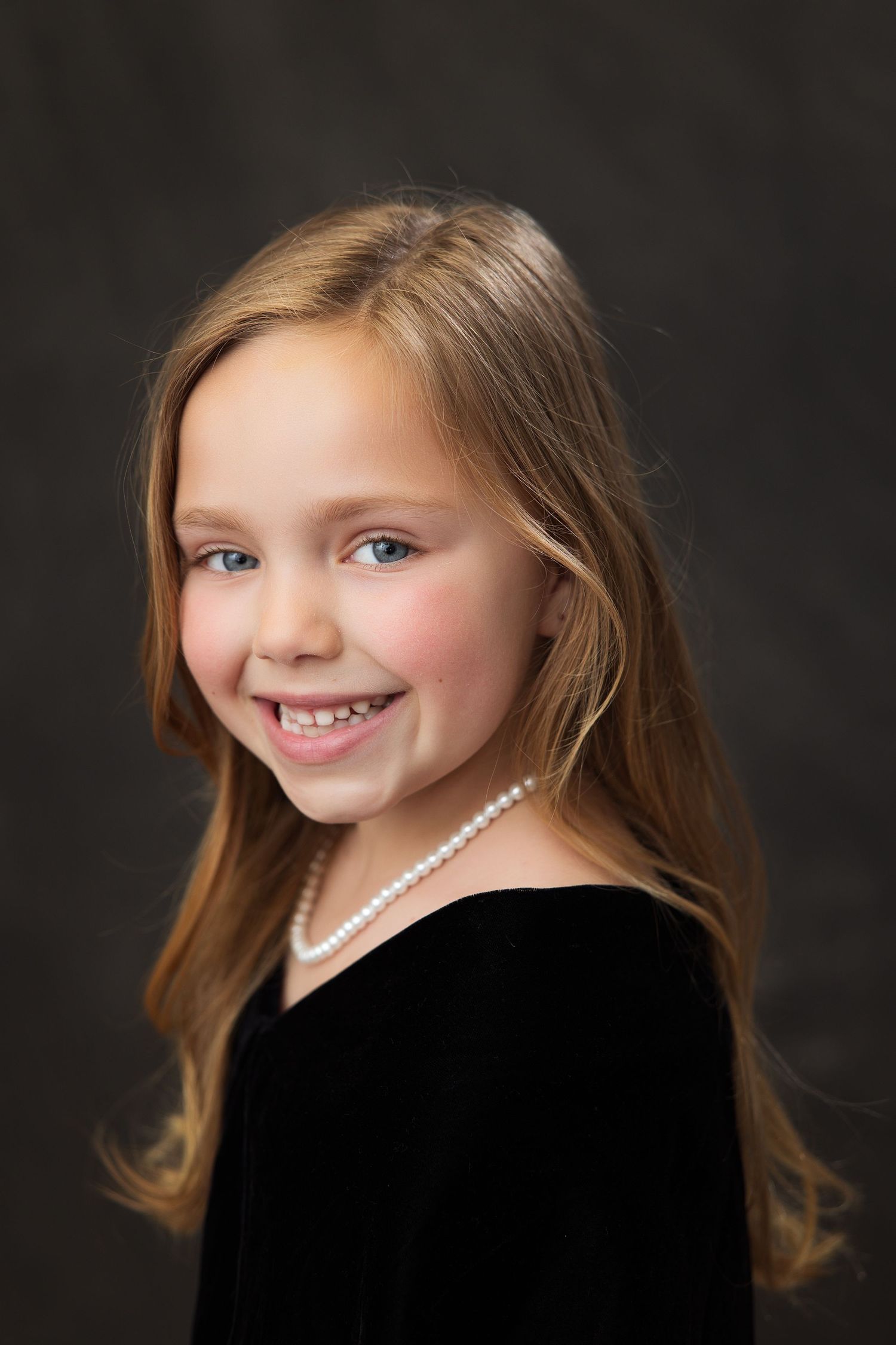 A portrait series in black flowing into multiple expression shots of a child in a black top against a dark background.