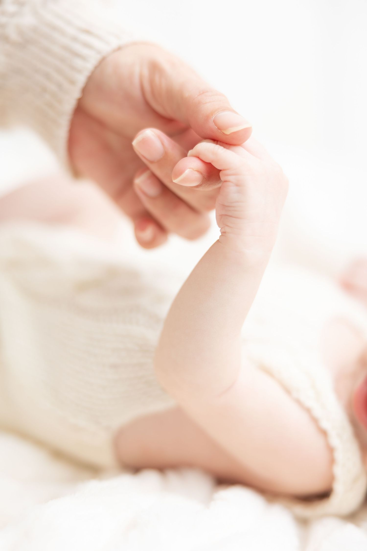 A newborn baby grasping an adult finger, symbolizing the bond between parent and child.