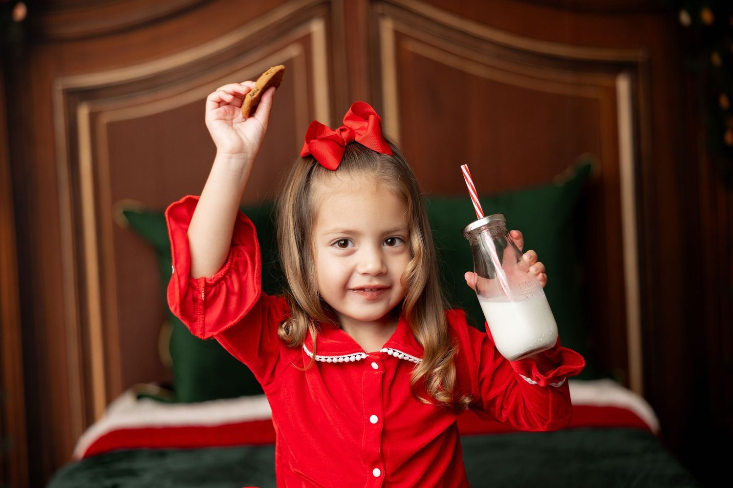 Little girl in red holiday jammies with a cookie and milk at a Milk & Cookies Christmas mini session in Pacific Grove