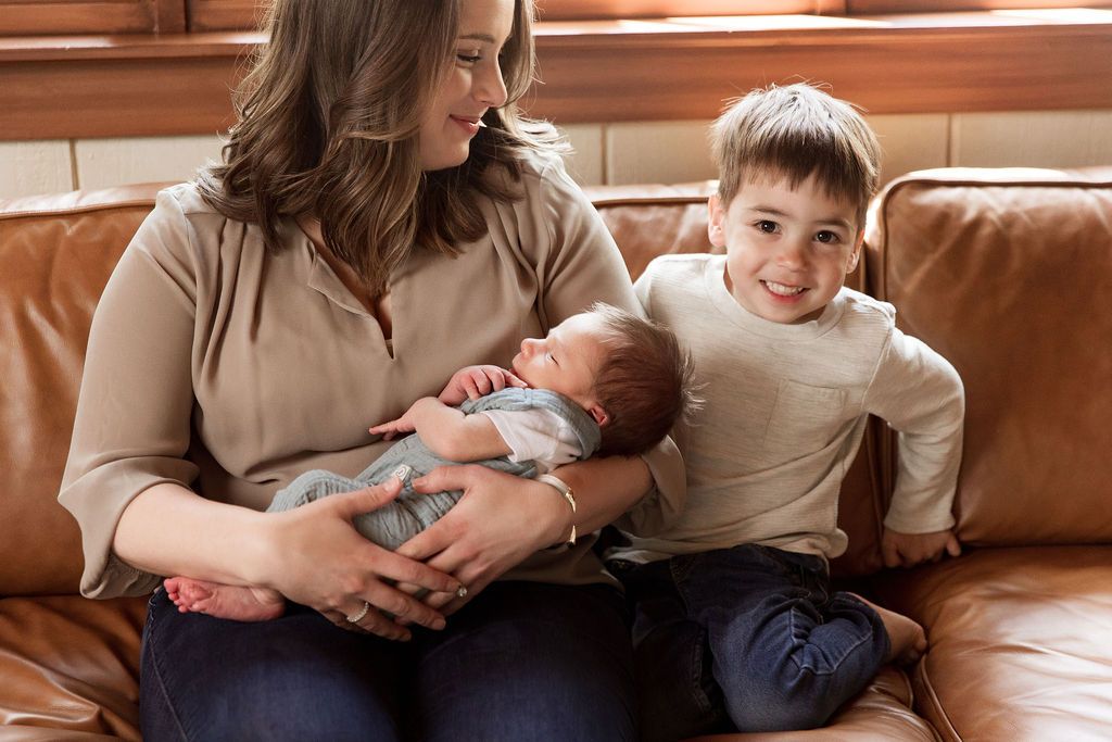 A series of intimate family moments captured in warm lighting on a brown leather couch with a newborn baby.