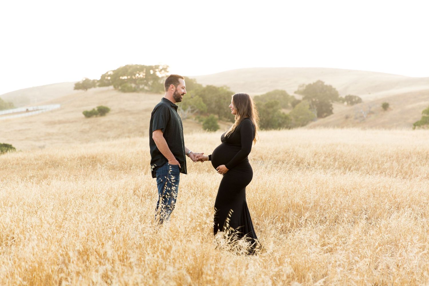 Family walking together through tall grass during golden hour.