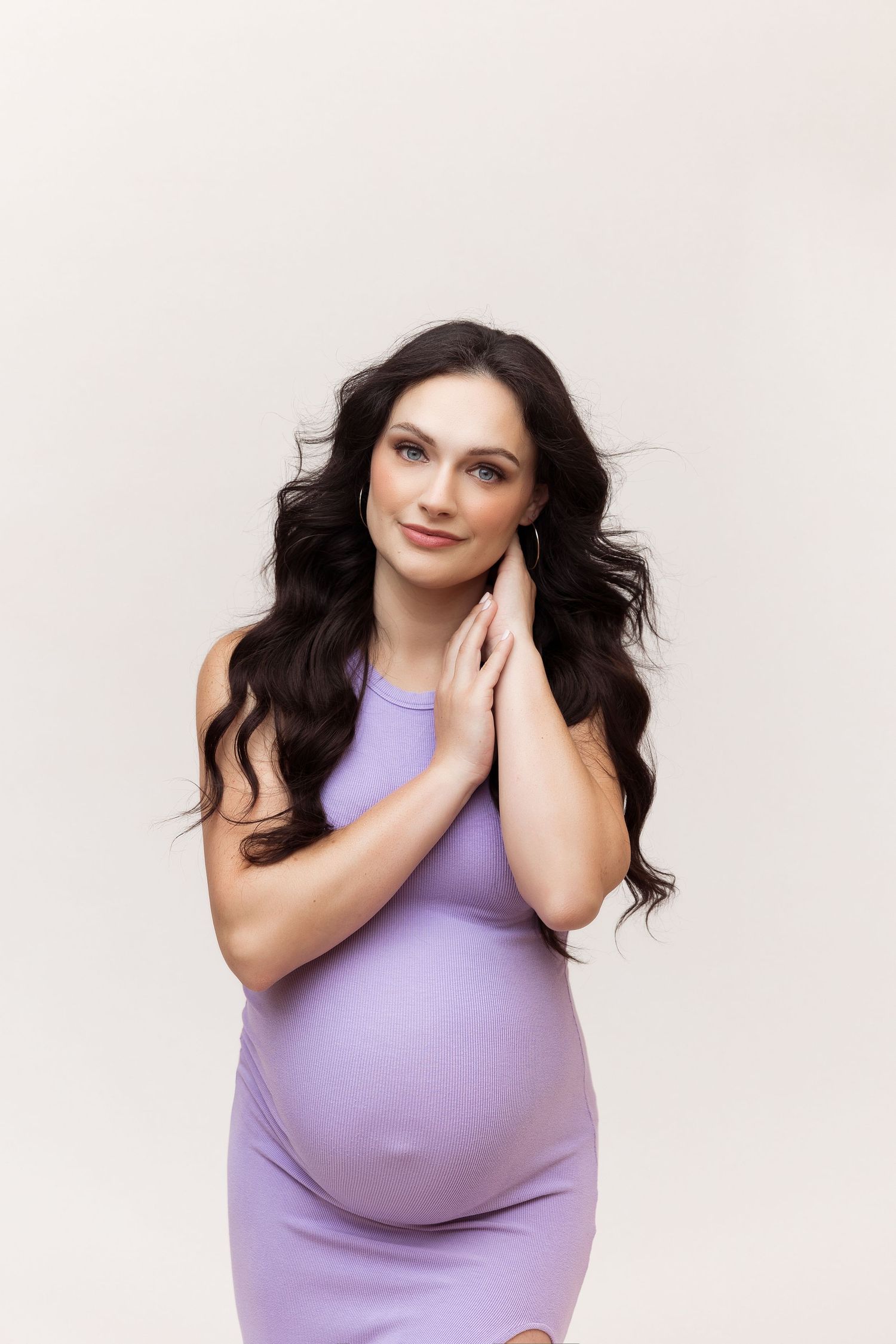Artistic maternity photo series with woman in violet sleeveless dress.