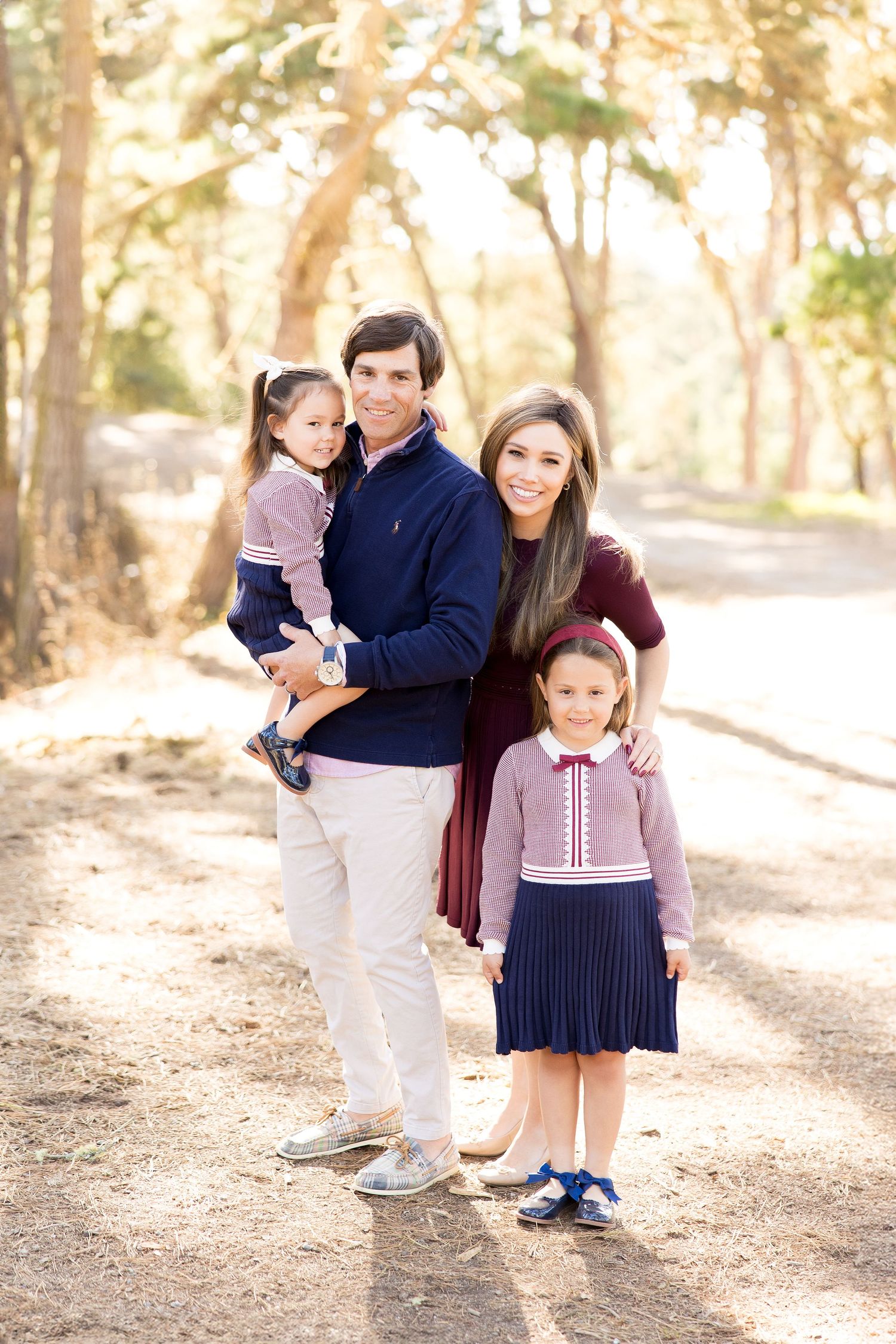 Family portrait session on a tree-lined path with warm lighting.