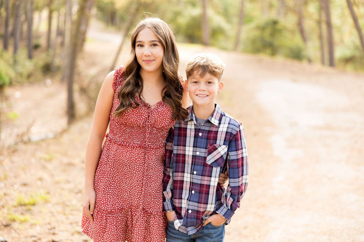 Two people pose together on a nature trail wearing casual outfits.