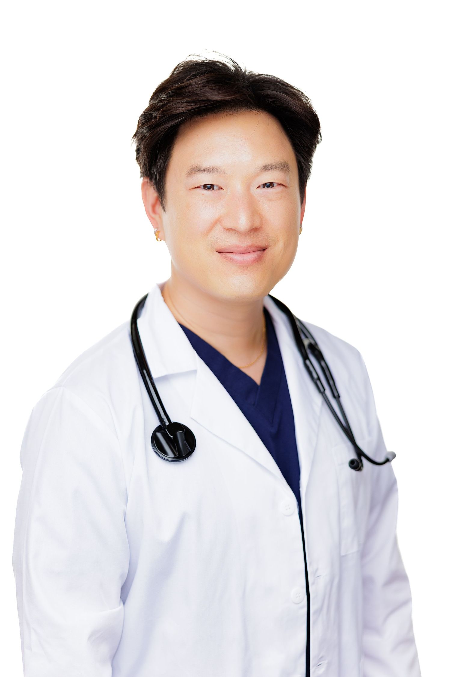 Smiling Asian male doctor in white lab coat and stethoscope poses confidently against white background.