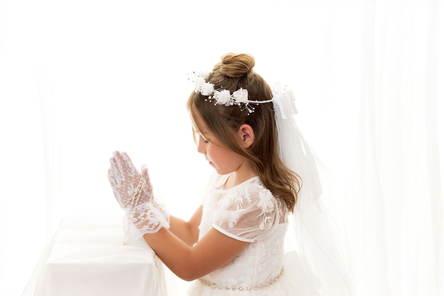 A bride in a white gown getting ready on her wedding day, adjusting lace gloves and accessories.