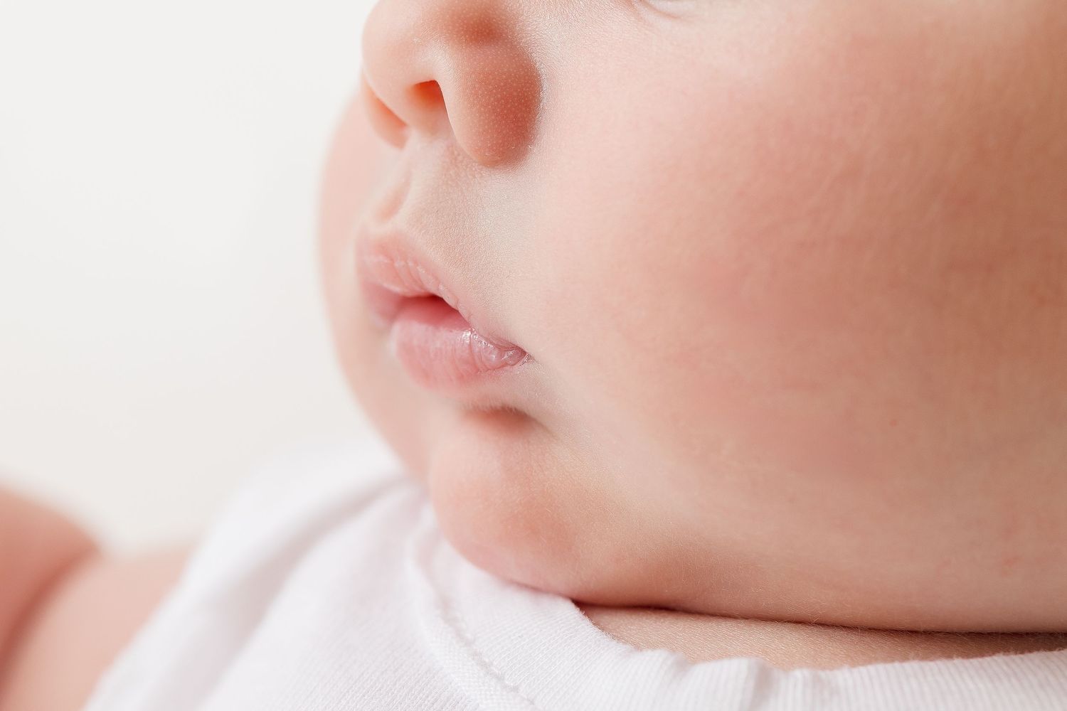Close-up macro shot showing soft pink lips and nose against a bright white background.