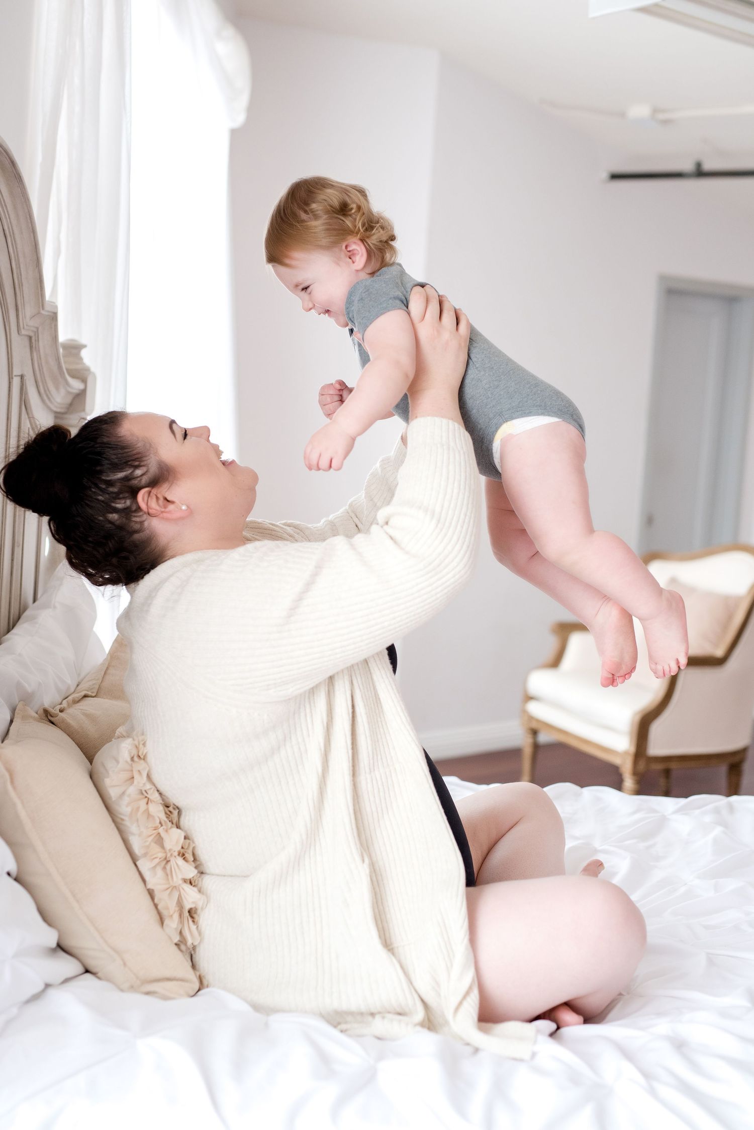 A tender moment of play between parent and child on a white bed.
